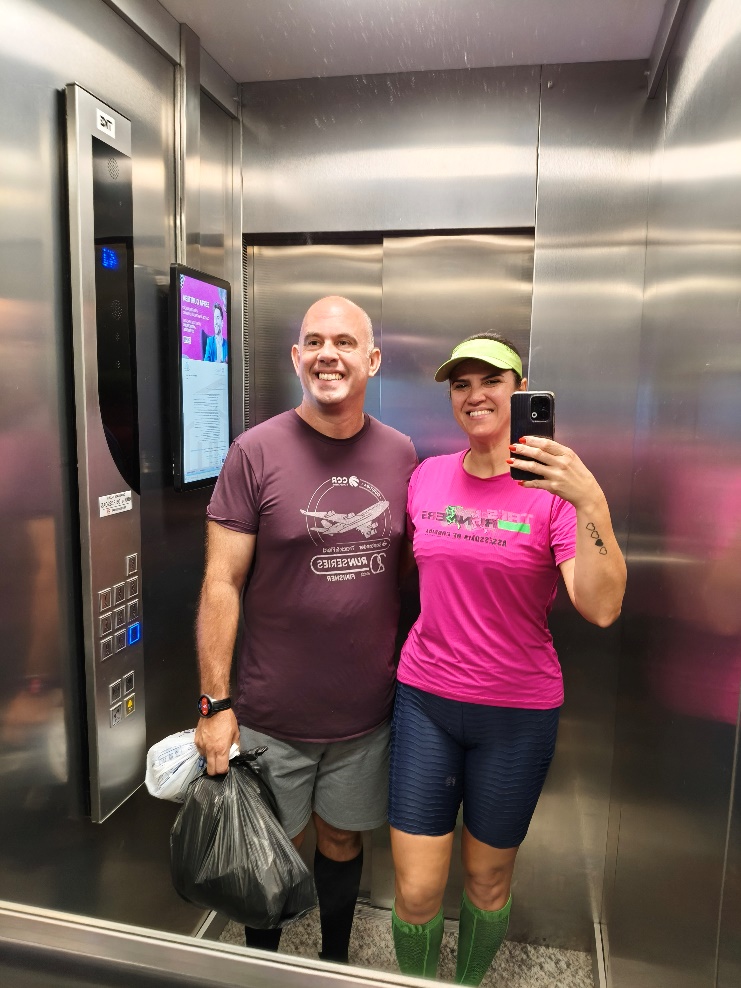Emanuel e Merielin em foto no elevador, representando parceria no dia a dia.